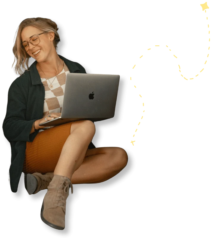 Alise Skiba, brand and web designer at Art of Kind Design, smiling while working on her laptop