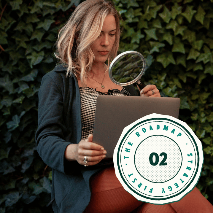 Alise Skiba holding a magnifying glass over her laptop in front of an ivy wall, with a “02 · The RoadMap · Strategy First” stamp